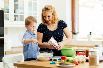 Smart cute child helping mother in kitchen