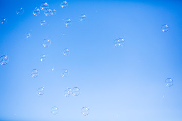 Soap bubbles in flight against the blue sky