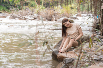 teen girl sitting  near waterfall