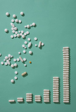 Pills scattered above capsules forming ascending bar graph on green backgrounds