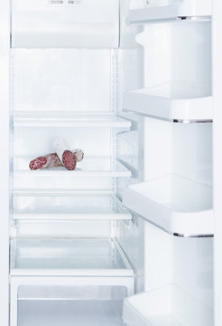 Salami in open, empty white refrigerator