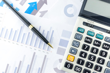 Calculator and pen with Business Graphs finance document.