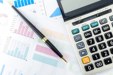 Calculator and pen with Business Graphs finance document.
