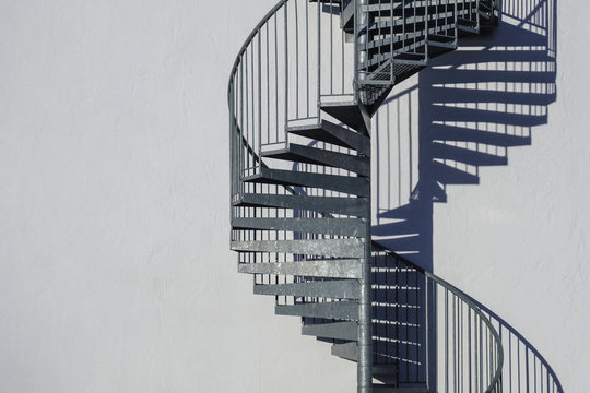 Spiral staircase along sunny wall