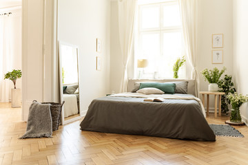 A natural bright apartment interior with wooden floor, white walls and sunny windows. A bed with...