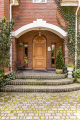 Fototapeta na wymiar Elegant, wooden entrance door to an estate with ivy growing on brick walls