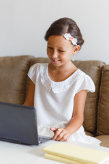 Beautiful, elegant girl 8 years old is engaged in home in an online school.

