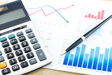 Calculator and Pen on Business Graphs finance document.