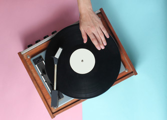 Female hands  use retro vinyl player on a blue pink pastel background. DJ. Top View.