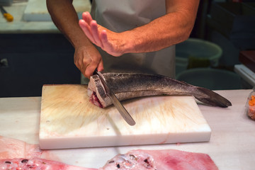 Man cutting slices of Mediterranean fish on Ataranzanas Central Market, Malaga, Spain