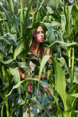 dark portrait of a teenage girl in a cornfield amongst plants and huge leaves