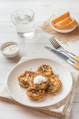 Fried zucchini slices in egg batter with garlic on a plate.
