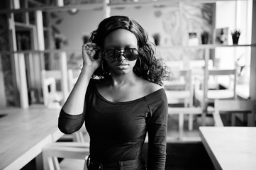 African american girl in sunglasses posed at modern cafe.