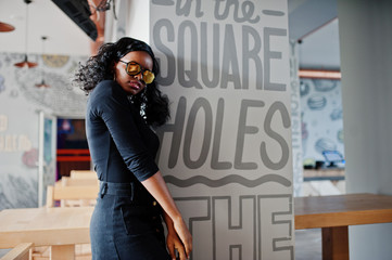 Obraz premium African american girl in sunglasses posed at modern cafe.