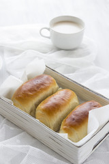 Brioche fatta in casa in cestino bianco con tazza di latte