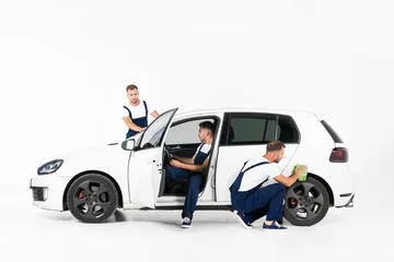 Foto op Canvas handsome auto mechanic cleaning and testing car after repairing on white © LIGHTFIELD STUDIOS