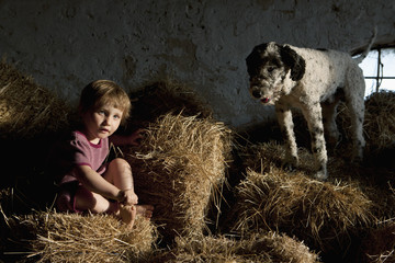 Portrait cute girl with dog sitting in hay