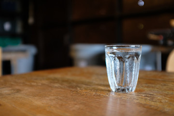 A glass of cold water on a wooden table with blurred background