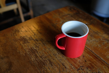 High angle view zoom out of a red cup of coffee on a rustic wooden table in a cafe