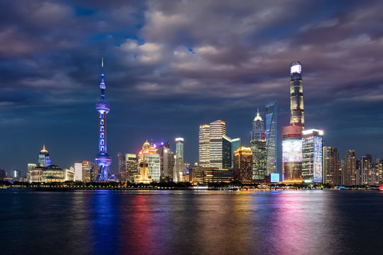 Die hell beleuchtete Skyline von Shanghai am Abend mit bewölktem Himmel, China