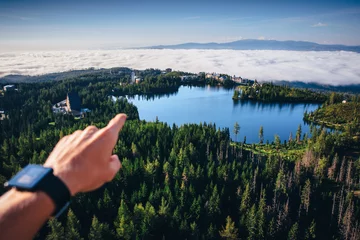 Poster Hand pointing to the beautiful nature on blue lake and mist in the valley © kovop58