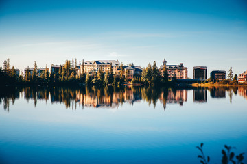 Fototapeta premium Luxury hotels by lake in mountains. Clear reflection in morning light