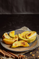 Baked pumpkin with spices in a plate on a dark background