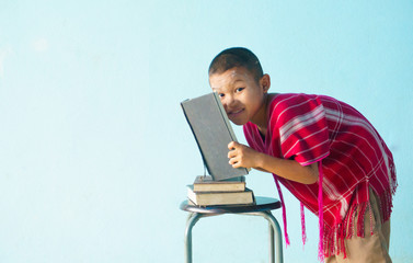 Little boy holding a large book on a light blue background.