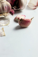 Garlic heads and cloves on white marble surface, copy space