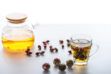 cup of chinese flowering tea, teapot and tea balls on table