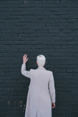 Woman standing and touching black brick wall