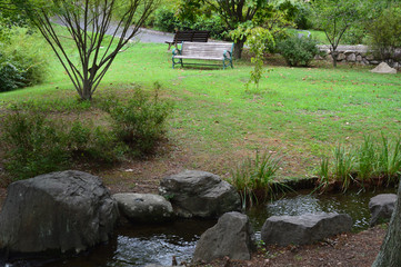 岩と小川とベンチがある庭園の風景