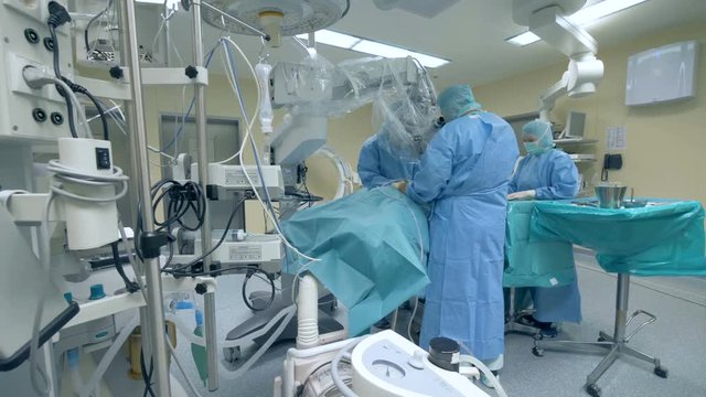 A group of surgeons is performing an operation in a medical unit