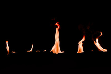 close up view of small burning orange fire on black backdrop