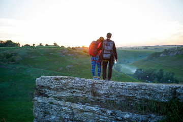 Photo from back of hugging man and tourist woman with backpacks on mountain