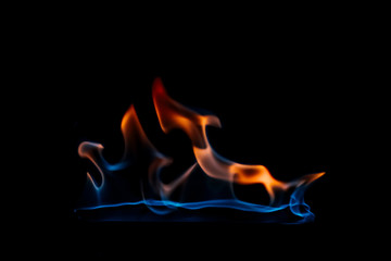 close up view of burning orange and blue flame on black background