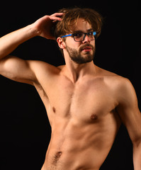 Man smart and sexy with beard and tousled hair wears eyeglasses. Man sexy muscular torso posing black background. Macho attractive nude guy nice belly six pack. Fit and attractive