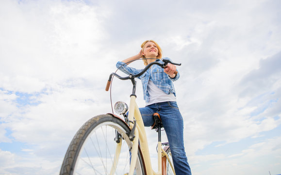 Girl rides bike sky background. Woman rent bike to explore city copy space. Bike rental shops primarily serve people who do not have access to vehicle typically travellers and particularly tourists