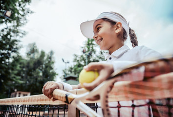 portrait of cute happy little girl playing tennis in summer