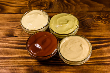 Different sauces in glass bowls on wooden table