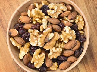 Delicious nuts arrangement in a wooden bowl. Close up shot of various nuts, healthy eating scene and wooden background. Top view.
