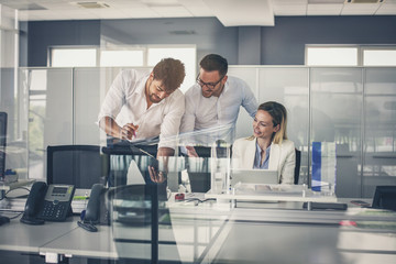 Three colleague in office reading document.