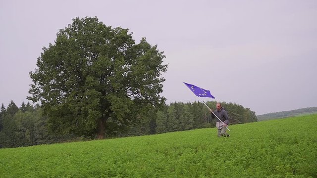 man is running with a flag of the European Union in country landscape. Standard Bearer