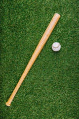 Fototapeta na wymiar top view of baseball bat and ball arranged on green lawn