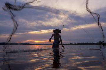 Fishermen are netting to catch fish in the lake on sunset