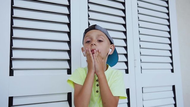 Attractive serious boy is closes and reveals his hands face while listening to music from the phone isolated at white background