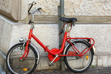Fototapeta na wymiar bicicletta pieghevole vintage rossa appoggiata a muro