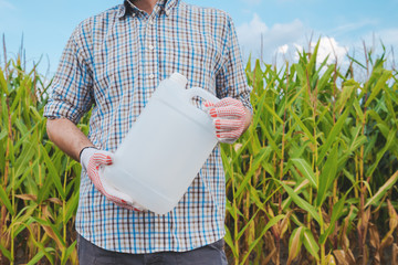 Farmer holding pesticide chemical jug in cornfield