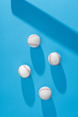 top view of arranged baseball balls and bat shadow on blue background