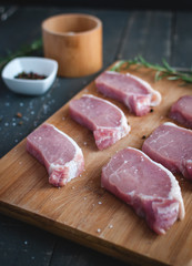 Close-up of raw pork chops on cutting board with seasonings